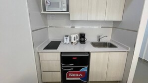 A compact kitchenette with a microwave, toaster, coffee maker, sink, and trash bin. - Moderno Y Comodo Estudio San Telmo (Buenos Aires)
