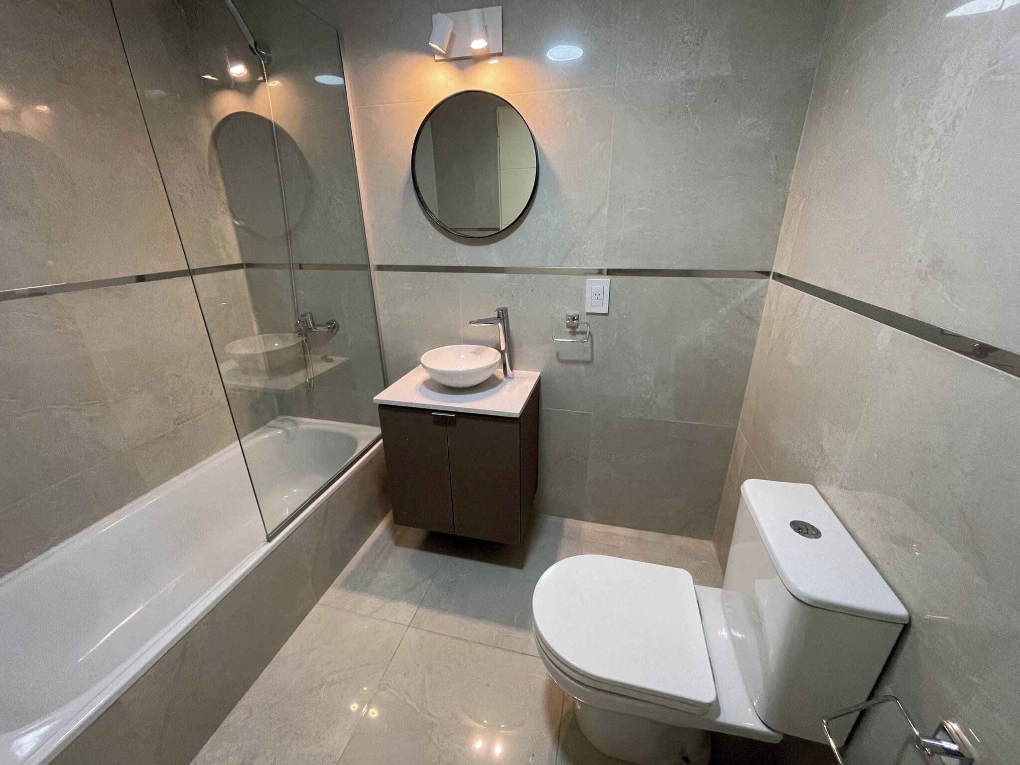 Un baño moderno con una bañera, un lavamanos con un espejo encima y un inodoro.