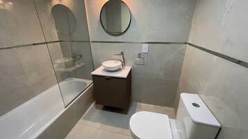Un baño moderno con una bañera, un lavamanos con un espejo encima y un inodoro.