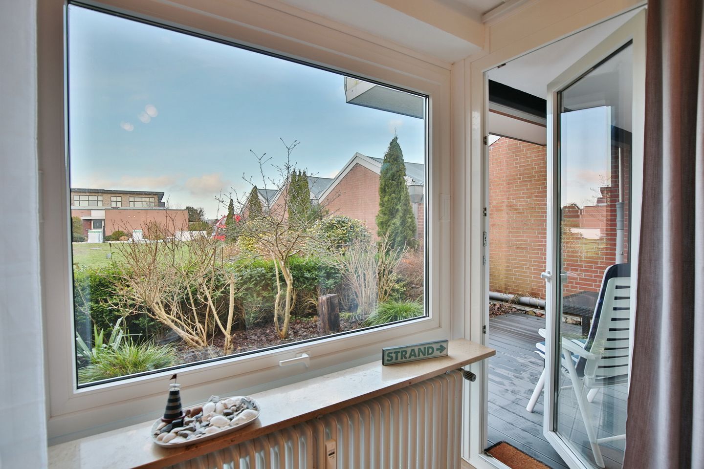A room with a large window overlooking a garden and a brick building.