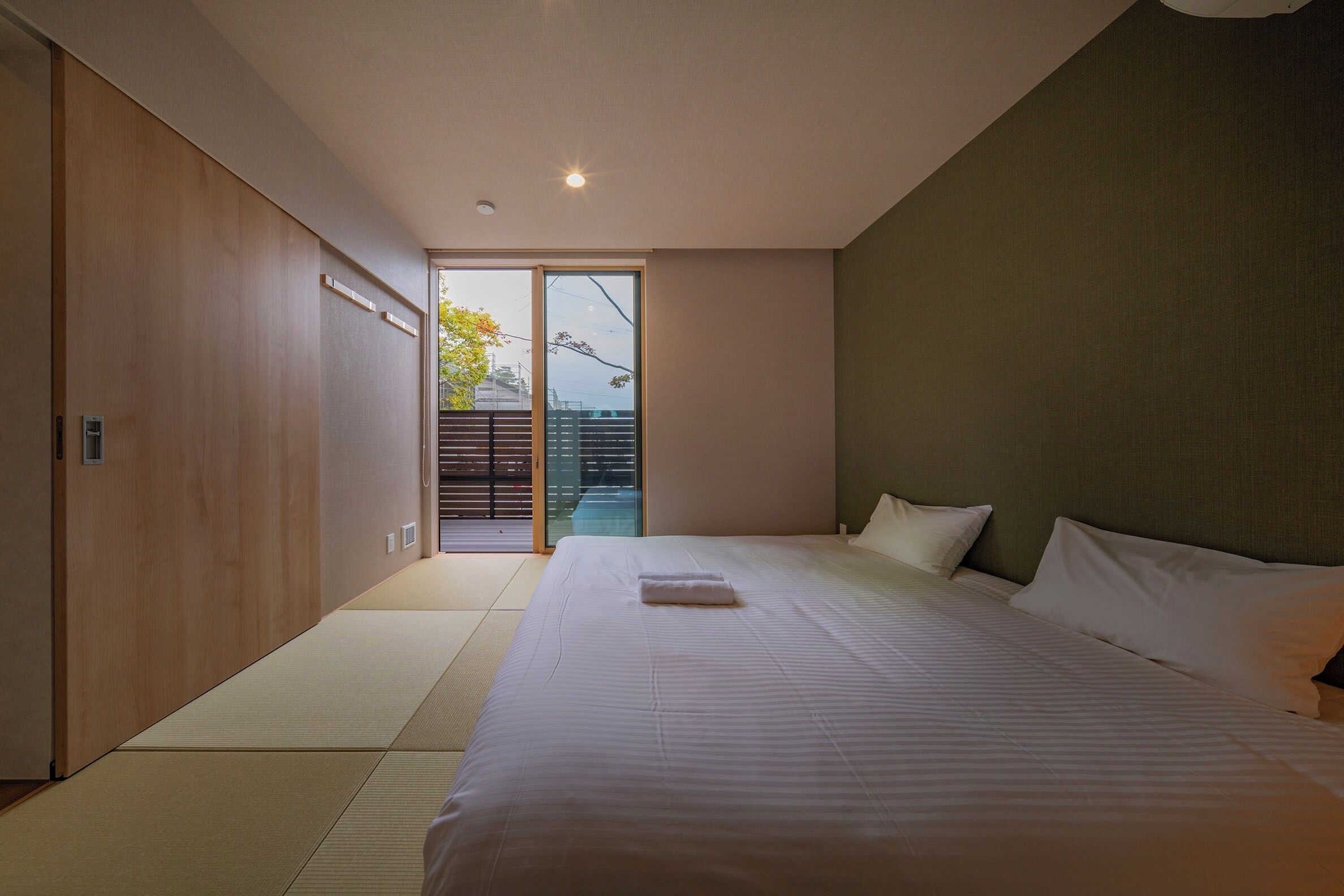 Een slaapkamer met een groot bed, een schuifdeur naar een balkon en uitzicht op de omgeving.