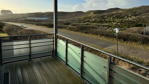 Varanda com vista para uma estrada e edifícios ao longe, emoldurada por paisagem natural.