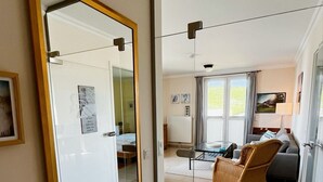 Uma sala de estar moderna com um espelho grande, uma cadeira de vime e um sofá.
