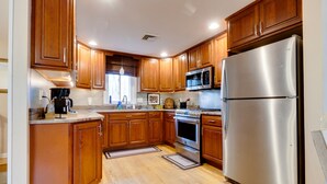 Une cuisine moderne avec des meubles en bois, des appareils en acier inoxydable et un plancher en bois.