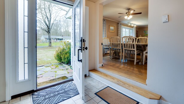 Un intérieur de maison comprenant un coin repas, un escalier menant à un deuxième étage et une vue sur le jardin à travers une porte vitrée.