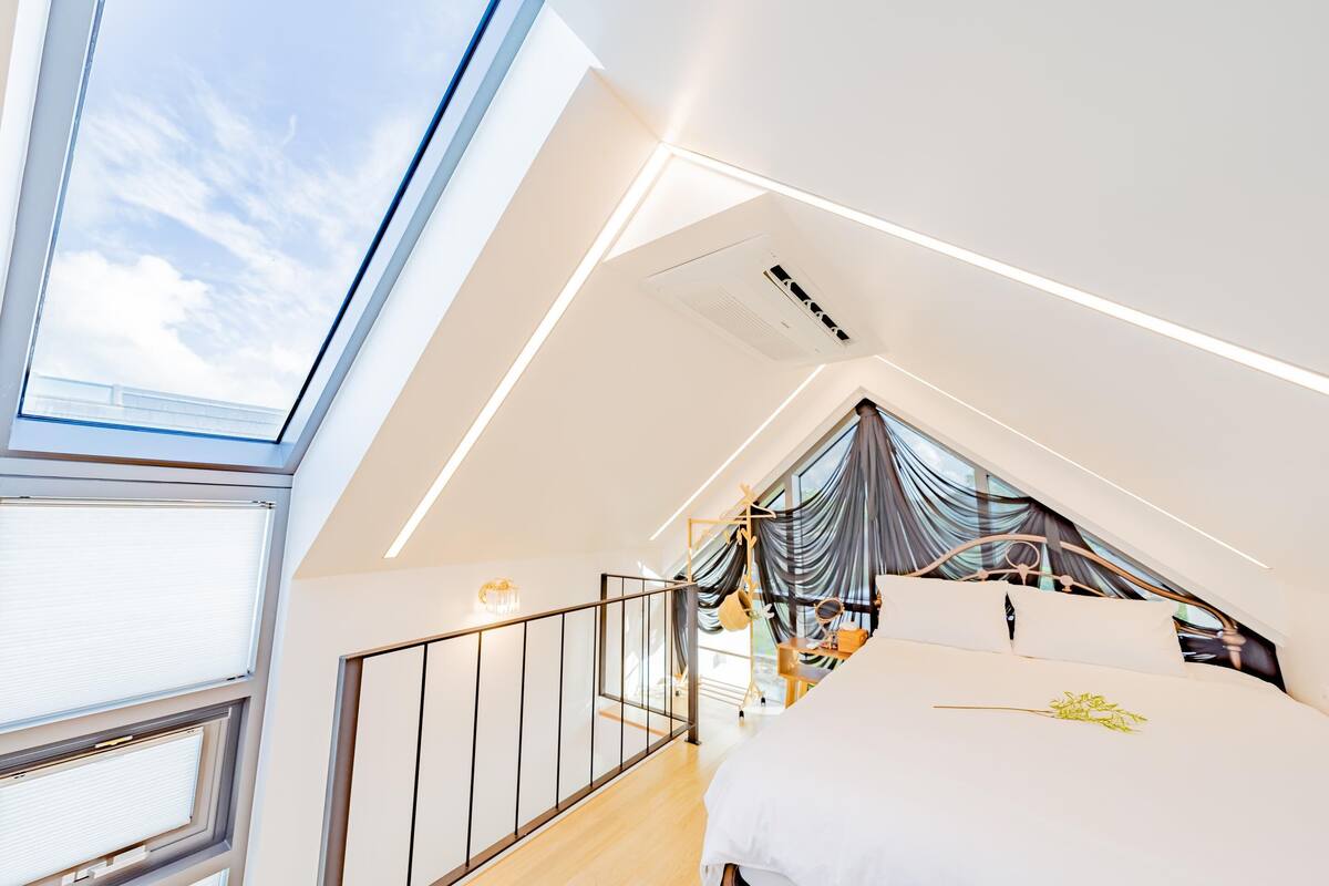 Un dormitorio moderno con tragaluces, una cama con ropa de cama blanca y vistas al cielo.