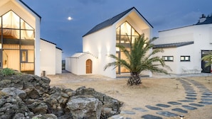 A modern building with large windows and a stone pathway leading to the entrance. - Jeju Geunalohu Pension (Jeju City)