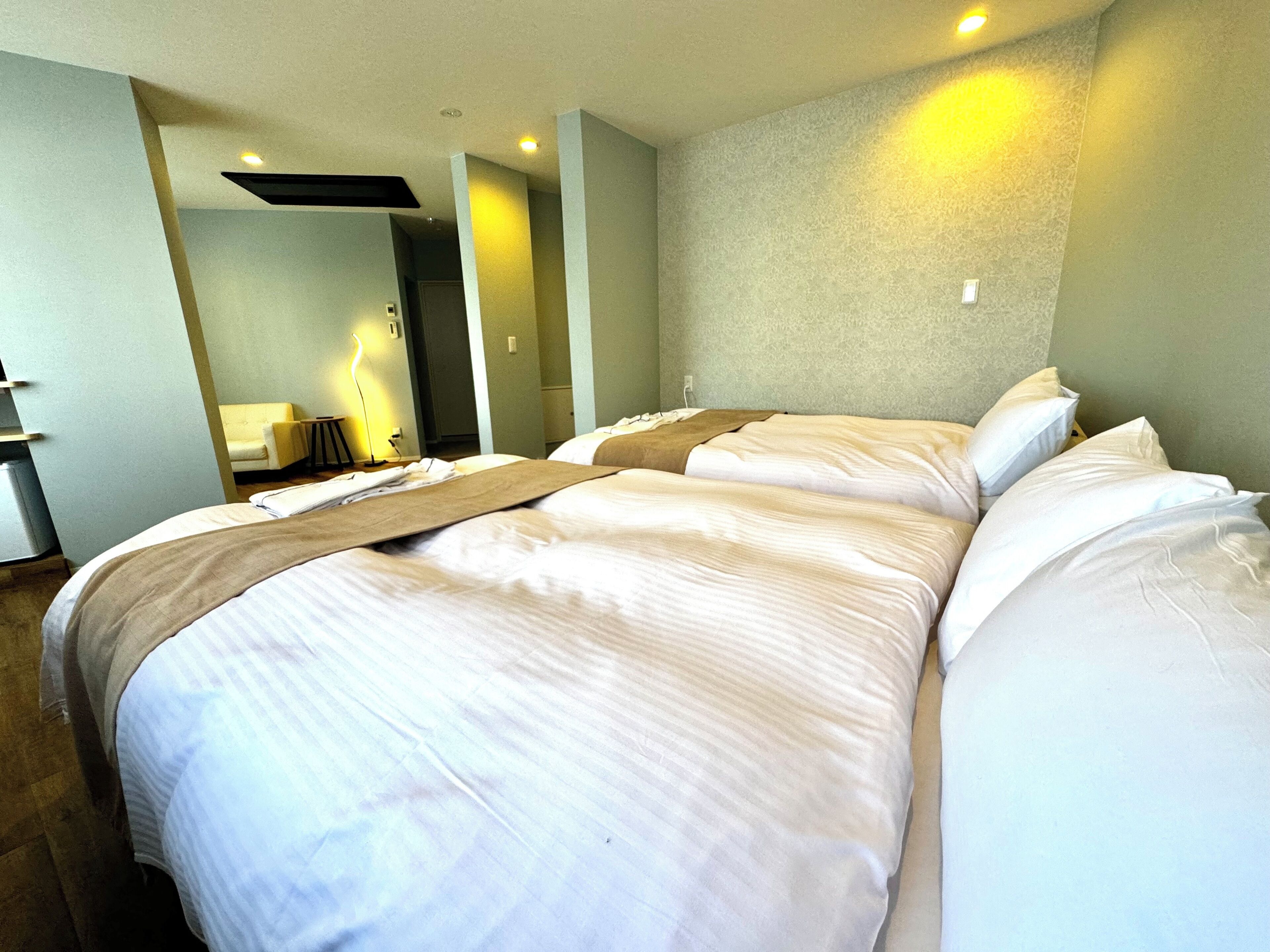 A hotel room with a large bed, a bedside table, a lamp, and a mirror.