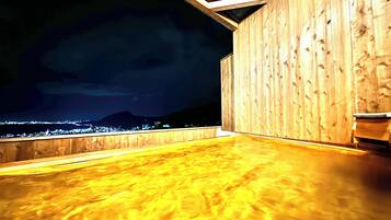 A wooden deck with a view of a cityscape at night.