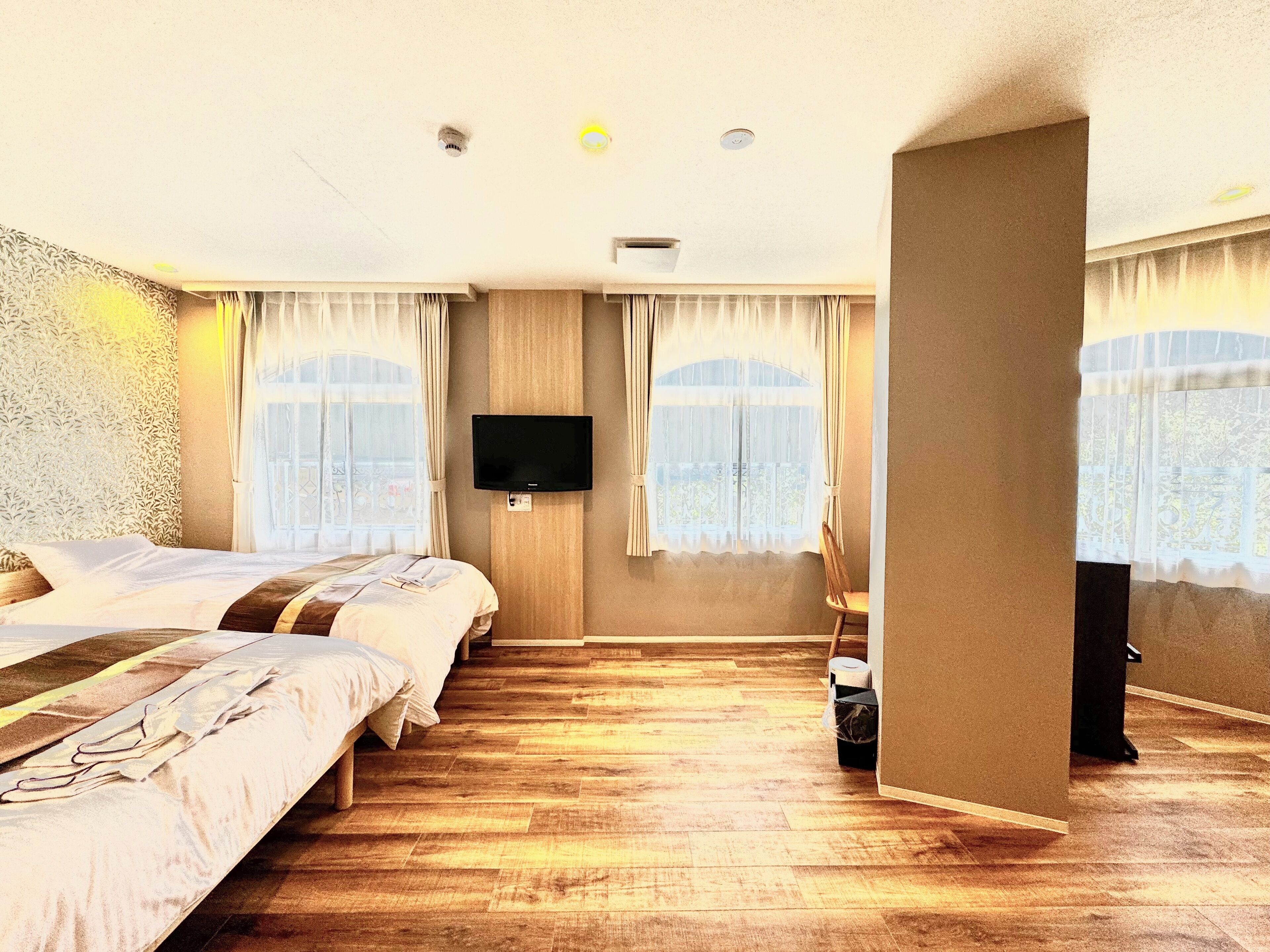 Habitació d'hotel amb dos llits, televisió de pantalla plana penjada a la paret i terra de fusta.