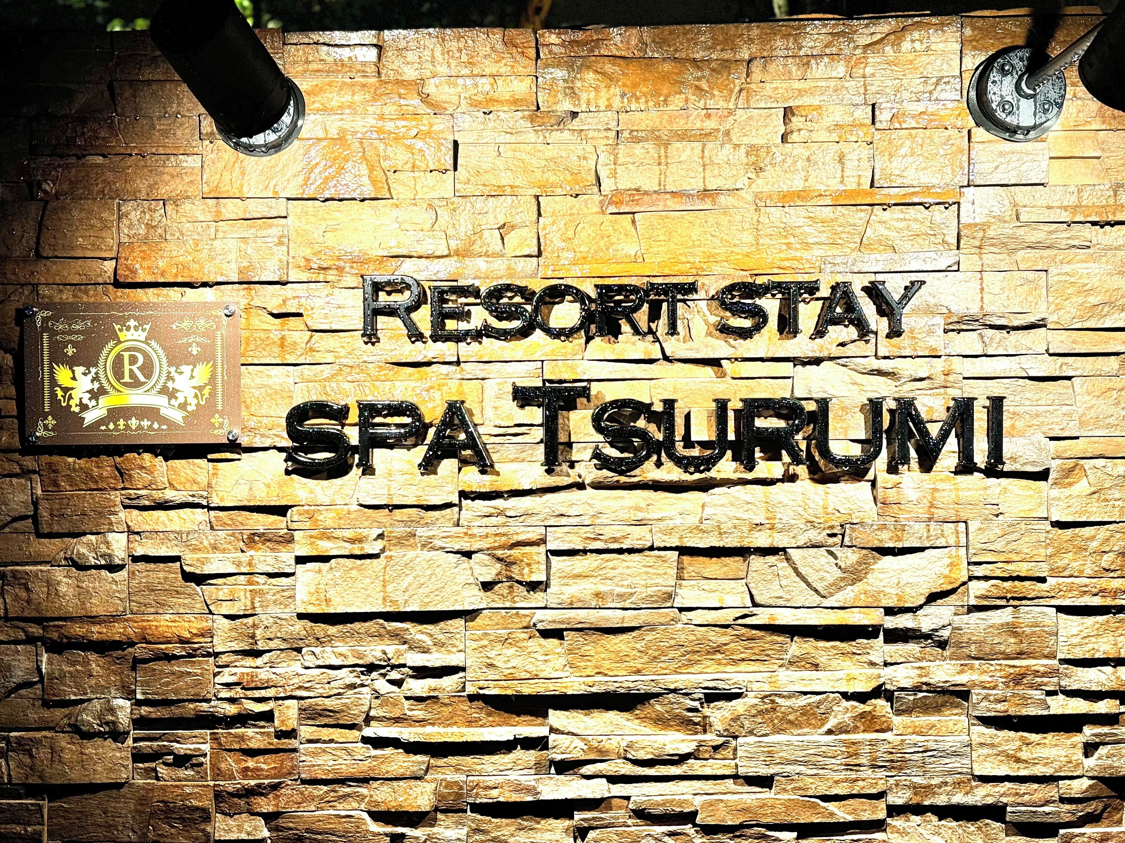 Pared de piedra con el texto "RESORT STAY SPA TSURUMI".