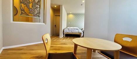 Une chambre moderne avec un plancher en bois, une table ronde, deux chaises, un lit et un élément décoratif mural.