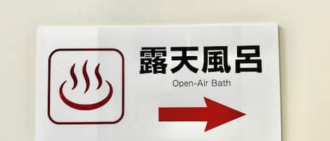 Señalización para un baño al aire libre con flecha indicadora.