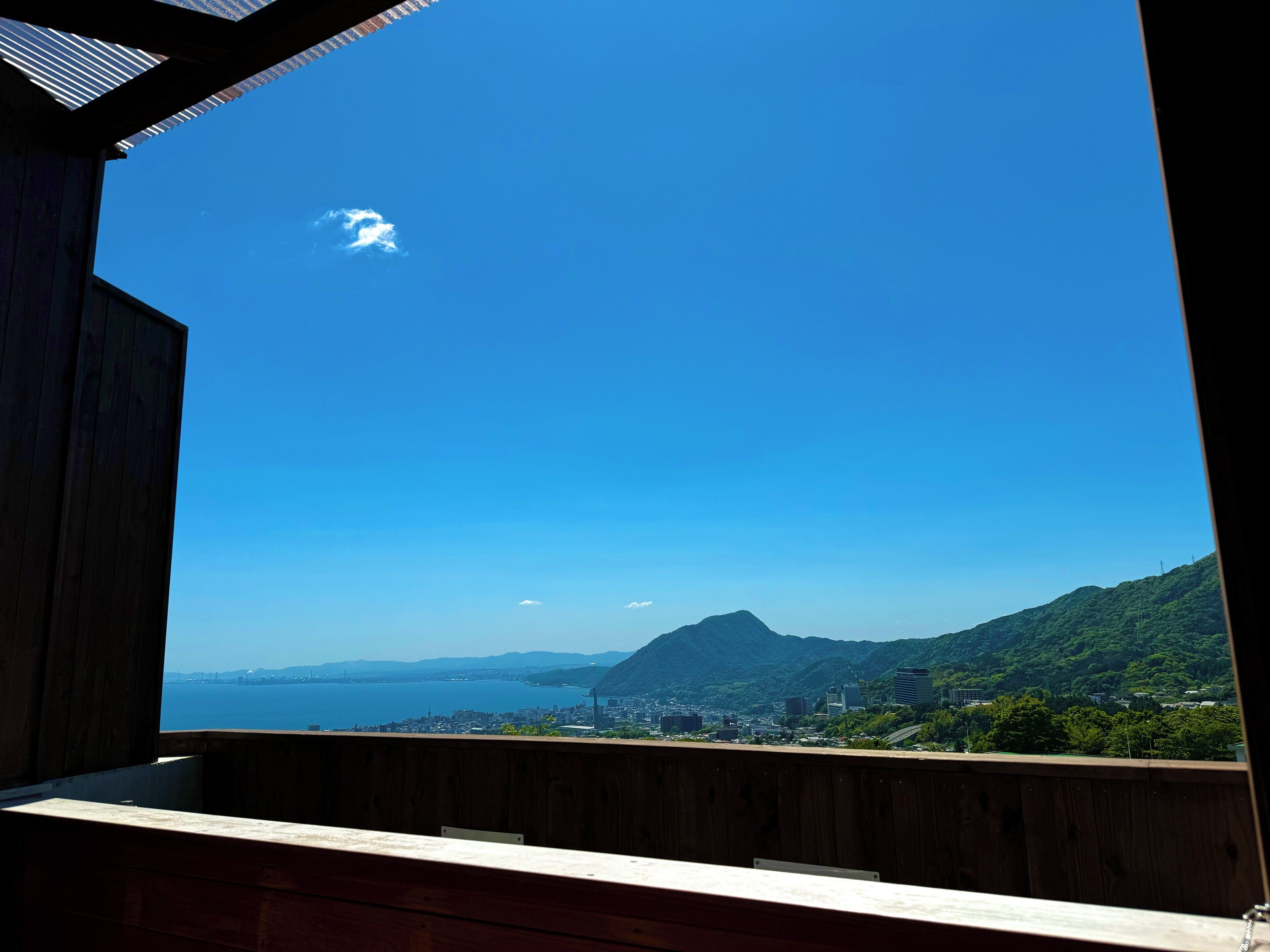 A wooden balcony with a clear view of a cityscape and mountains.