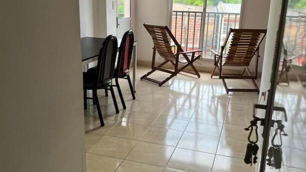 A spacious balcony with two wooden rocking chairs and a dining table with chairs.