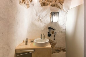 A bathroom with a stone wall, a white sink, and a handheld showerhead. - Tenuta Bouganville With Garden And Pool, Carpignano Salentino, Italy (Carpignano Salentino)