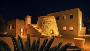 A building with a stone staircase leading to a door, a modern building with windows, and a large planter in the foreground.