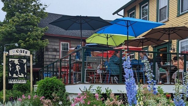 Un ristorante con posti a sedere all'aperto, circondato da una varietà di fiori e piante colorate.