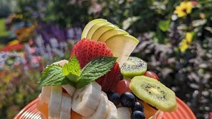 Un dessert su un piatto, con un sottopiattino in pizzo, circondato da fiori e piante colorate.