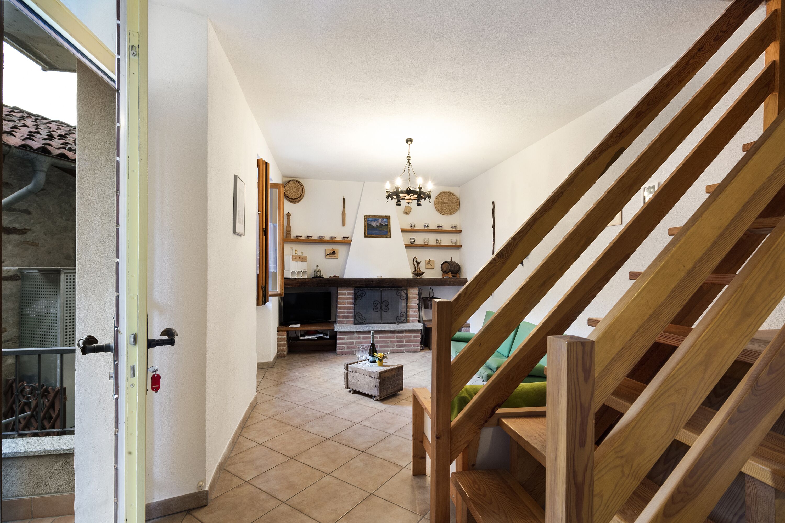 Un vaste espace de vie doté d’une cheminée, d’un escalier en bois et offrant une vue sur l’extérieur.