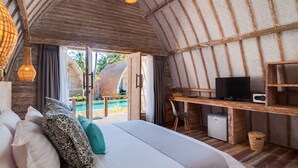 Een kamer met een bed, een bureau, een televisie en een kleine koelkast.
