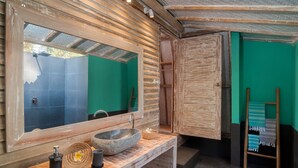 Een badkamer met een houten wastafelmeubel, een grote spiegel en een groene wand.