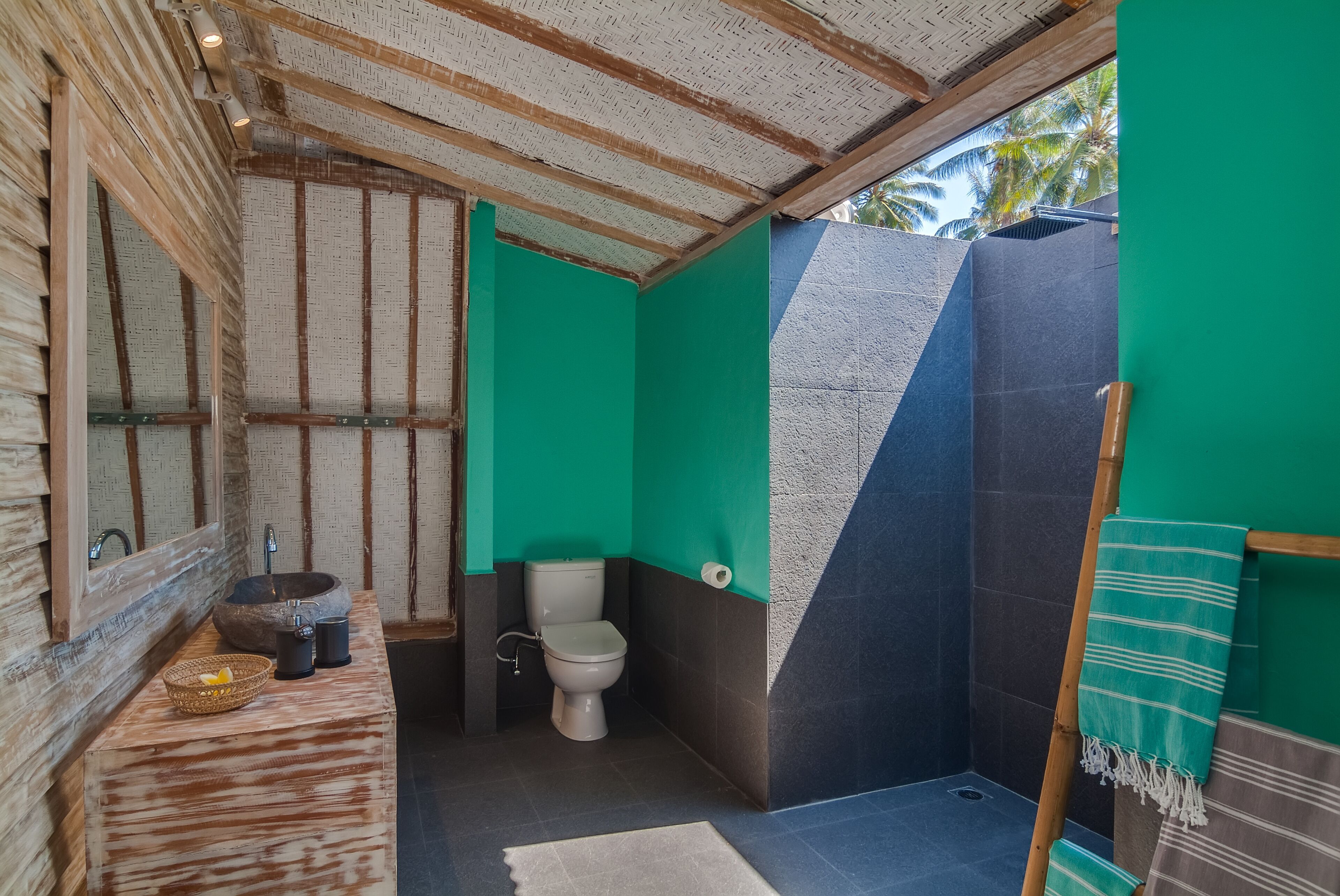 A bathroom with a wooden ceiling, a green wall, a white toilet, and a shower area.
