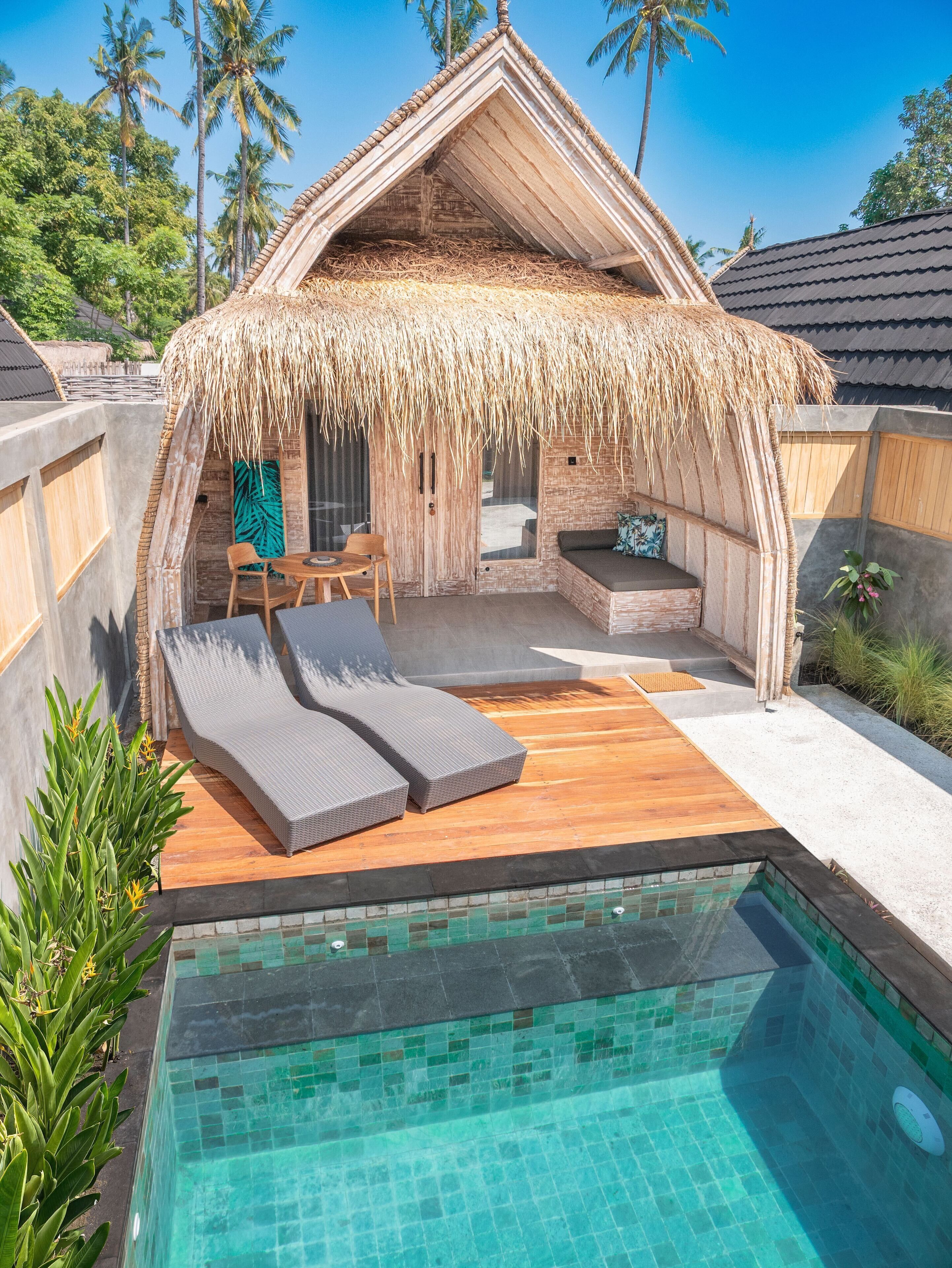 A thatched-roof structure with a pool and lounge area.