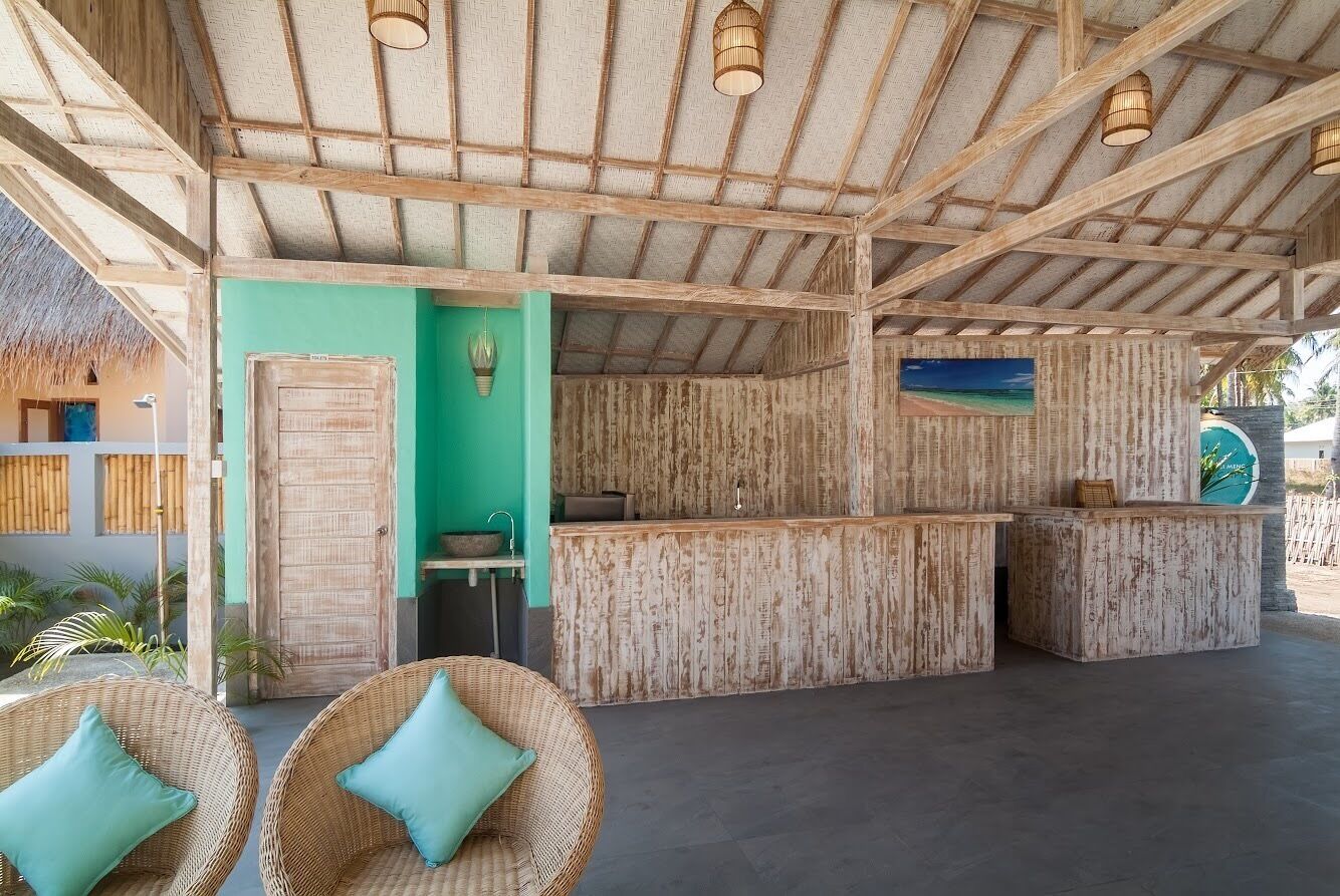 A beachside reception area with wooden furniture, a reception desk, and a view of the ocean.