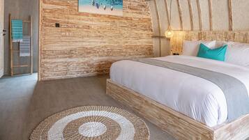 A cozy room with a wooden ceiling, a bed with white bedding, a painting on the wall, and a woven rug.