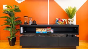 A modern living room with a black entertainment unit, a large plant, and a TV mounted on the wall.