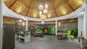 A spacious indoor area with a high ceiling, a central dining table with chairs, and a refrigerator. - Brand New Luxury 3BR Villa Ethnic Ubud 3 (Ubud)