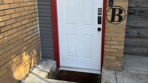 A white door with a red frame, a small window above it, and a mailbox with a 'B' logo. - Charming Midtown Studio: Steps to Ice Blocks (Sacramento)