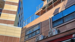 Un edificio a più piani con un design architettonico moderno, caratterizzato da ampie finestre e condizionatori d'aria sulla facciata.