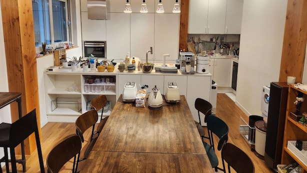 Una cucina moderna con travi in legno, mobili bianchi e un'isola centrale con elettrodomestici.