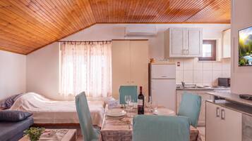 A compact living space with a kitchenette, a dining area, and a bedroom.