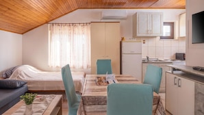 Una habitación compacta con cama, una mesa de comedor con sillas, kitchenette y televisión.