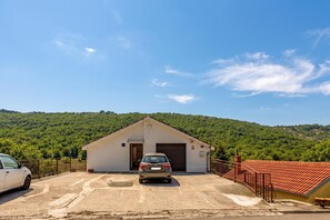 A building with a garage, a parked car, and a red-roofed structure. - Studio Apartment Iva Rijeka Suburbs (Rijeka)