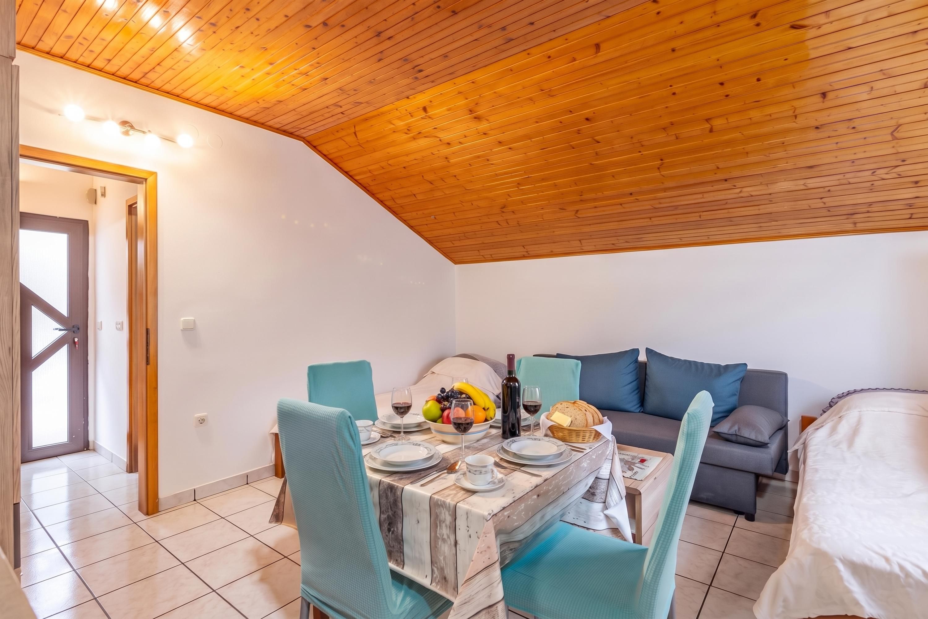 A cozy room with a dining table set for two, a sofa, and a bed.