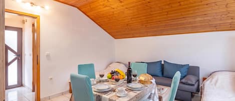 A cozy room with a dining table set for two, a sofa, and a bed.