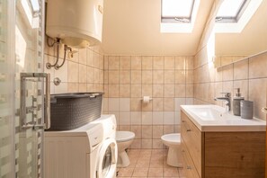 A compact bathroom with a washing machine, two toilets, a sink, and skylights. - Studio Apartment Iva Rijeka Suburbs (Rijeka)