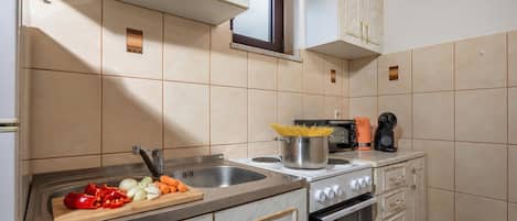 A kitchen with a sink, stove, oven, and cabinets.