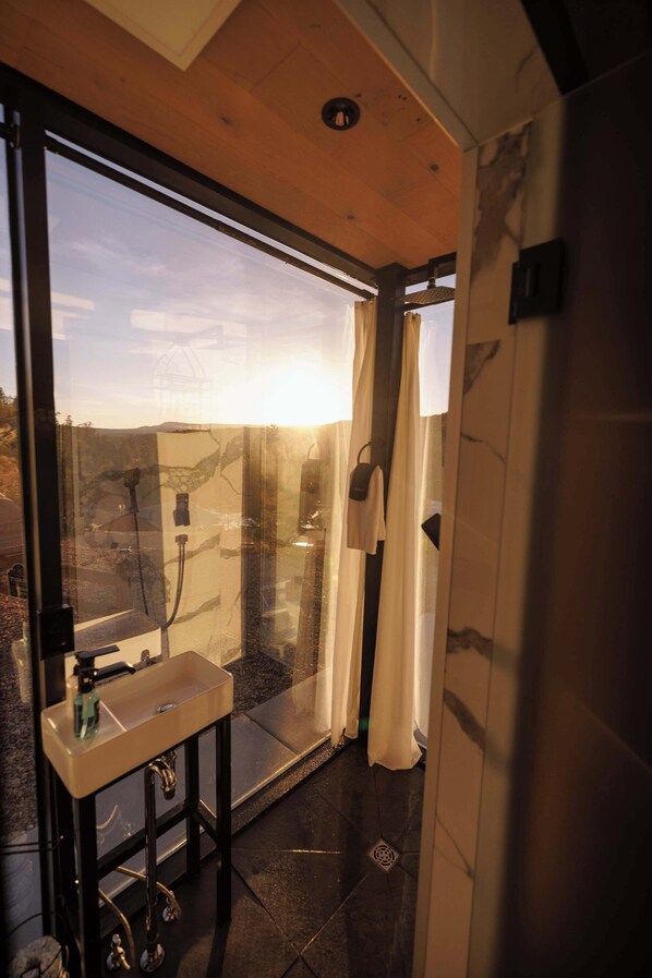 A modern bathroom with a glass shower enclosure, a sink, and a mirror.
