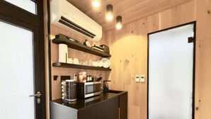 Une cuisine compacte équipée d’un four à micro-ondes, d’une machine à café et d’étagères où sont rangés la vaisselle.