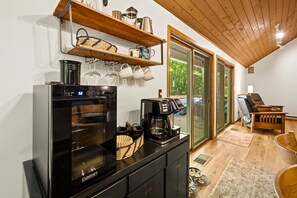 Una kitchenette con horno Cuisinart, cafetera y repisa con utensilios de cocina.