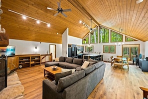 A spacious living area with a large sofa, wooden flooring, a kitchen, and large windows. - Luxury Chalet – Ephraim (Ephraim)