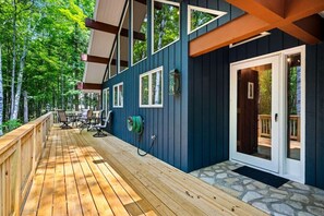 A wooden deck with outdoor furniture, a covered patio area, and a stone entryway.