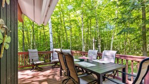 Eine Terrassenauslauf mit Tisch und Stühlen, umgeben von einem Wald.