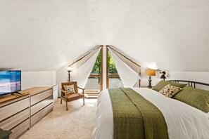 Une chambre à coucher avec un lit, une chaise, un bureau, une télévision et une fenêtre avec des rideaux.