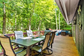 Une terrasse extérieure avec une table et des chaises, entourée d’une forêt.